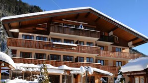 Un edificio de madera de varios pisos con balcones, un restaurante y alrededores cubiertos de nieve.