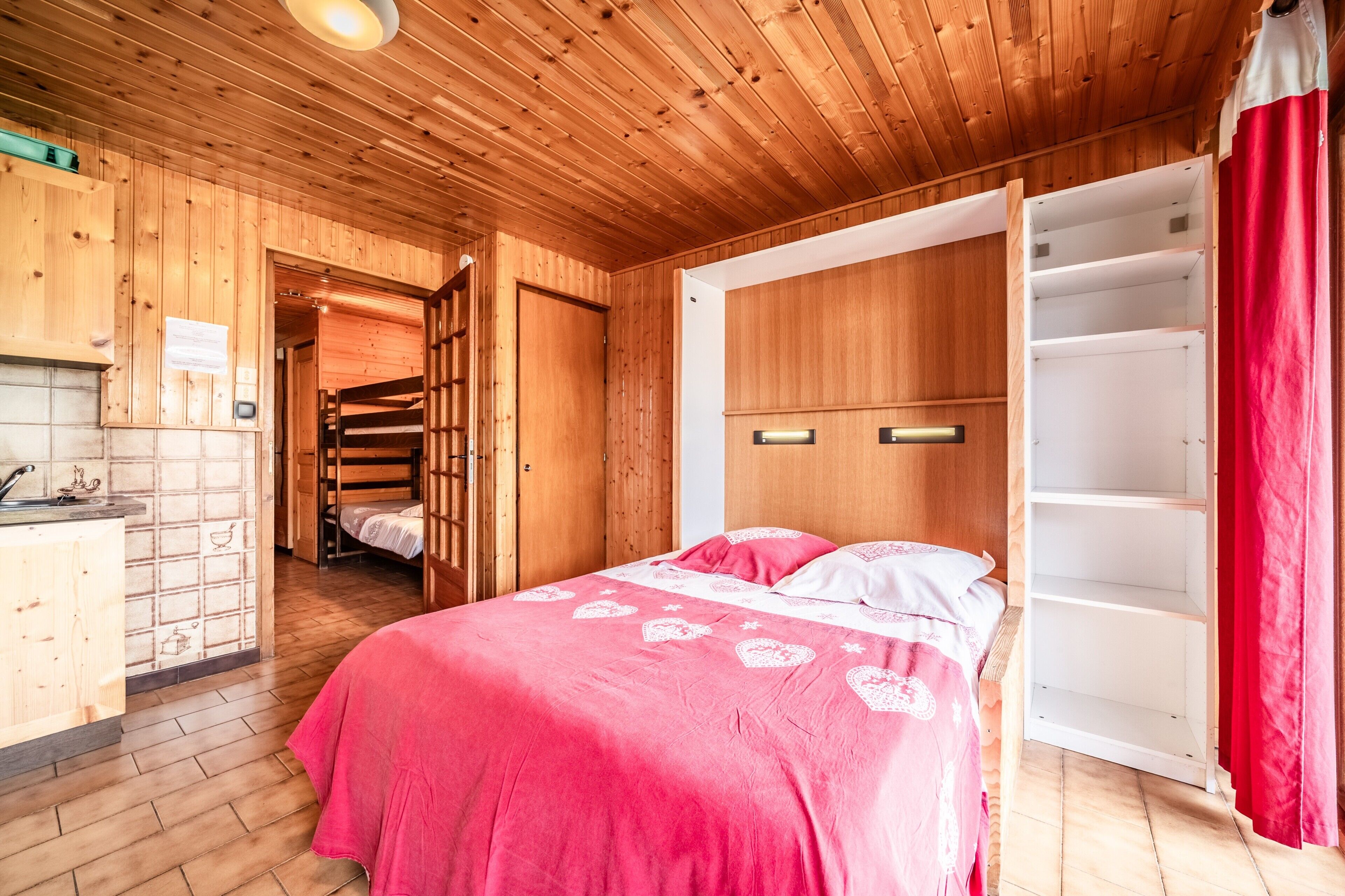 Un interior de madera con una cama, un armario y una zona de cocina.