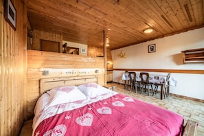 Ein Zimmer mit Holzboden, einem Bett, einer Essecke mit Stühlen und einem Tisch.