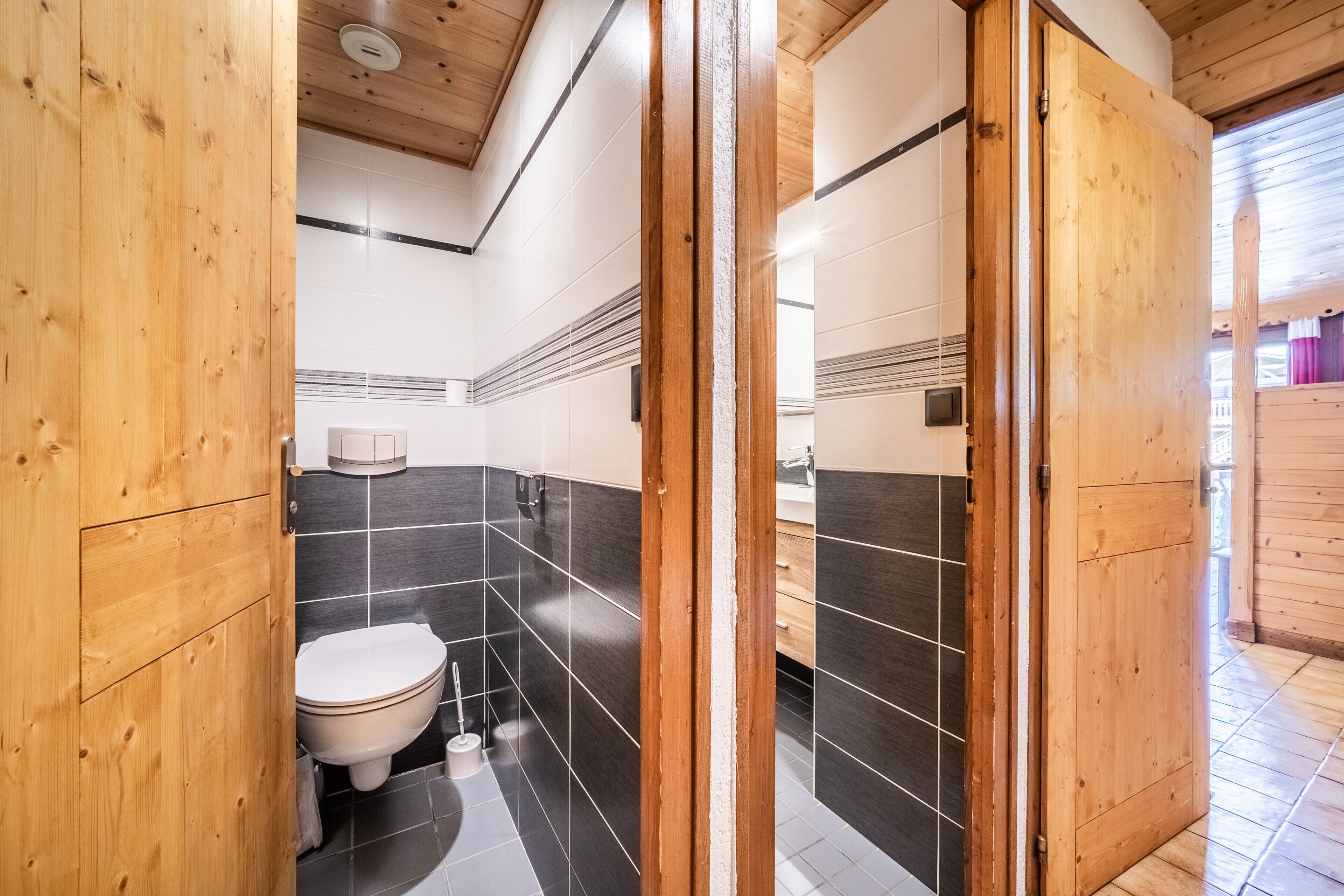 A wooden-paneled bathroom with a toilet, a hand dryer, and a towel rack.