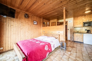 Eine Holzhütte mit einem Bett, einer Küche und einem Fernseher.