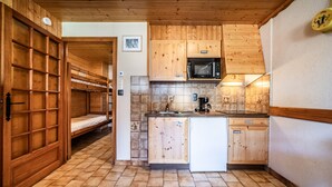 A compact kitchen with wooden cabinets, a microwave, a sink, and a dishwasher.