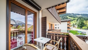 A balcony with a table and chairs, a view of a mountain, and a wooden railing. - Studio Apartment 'Le Blanchot - 4 Pers' with Mountain View, Balcony and Wi-Fi (Châtel)