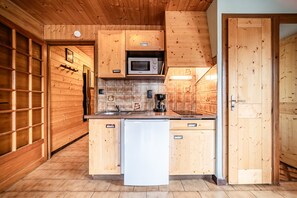 Une cuisine avec des meubles de rangement en bois, un four à micro-ondes et un réfrigérateur.
