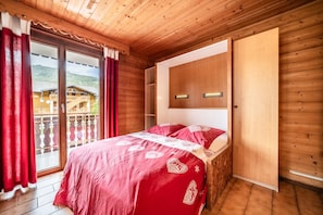 A wooden-paneled room with a bed, a sliding door, and a view of a mountain.