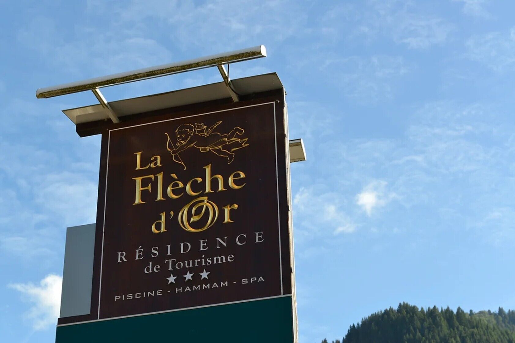 Une enseigne pour « La Flèche d'Or », avec un logo, indiquant qu’il s’agit d’un hôtel ou d’un complexe hôtelier.
