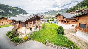 A mountain resort with wooden cabins, a grassy courtyard, and a view of the surrounding hills.