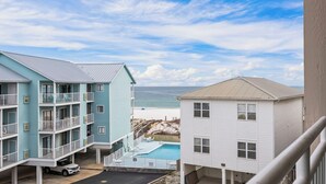 A beachfront building with a pool, balconies, and a view of the ocean.