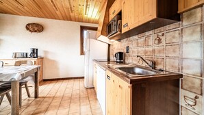 Een keuken met houten kastjes, een betegelde spatwand, een spoelbak en een fornuis.