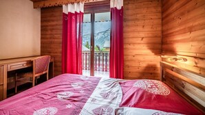 Una habitació de fusta amb un llit, un escriptori i una cadira.
