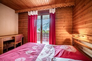 A wooden room with a bed, a desk, and a chair.