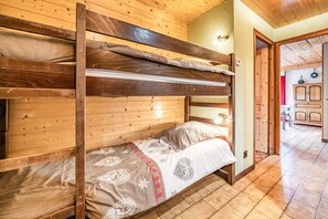 A bunk bed with a patterned bedspread, wooden walls, and a tiled floor. - Apartment 'La Flèche De Vermeil - 6 Pers' with Mountain View, Balcony and Wi-Fi (Châtel)