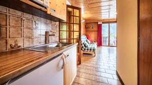 Une cuisine avec des meubles de rangement en bois, un évier et une fenêtre donnant sur un balcon.