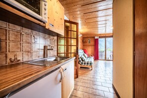 A kitchen with wooden cabinets, a sink, and a window overlooking a balcony.