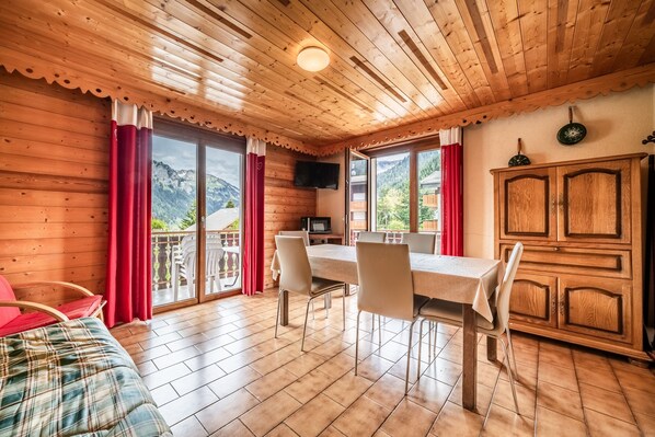 A wooden cabin with a dining area, a TV, and a view of mountains. - Apartment 'La Flèche De Vermeil - 6 Pers' with Mountain View, Balcony and Wi-Fi (Châtel)