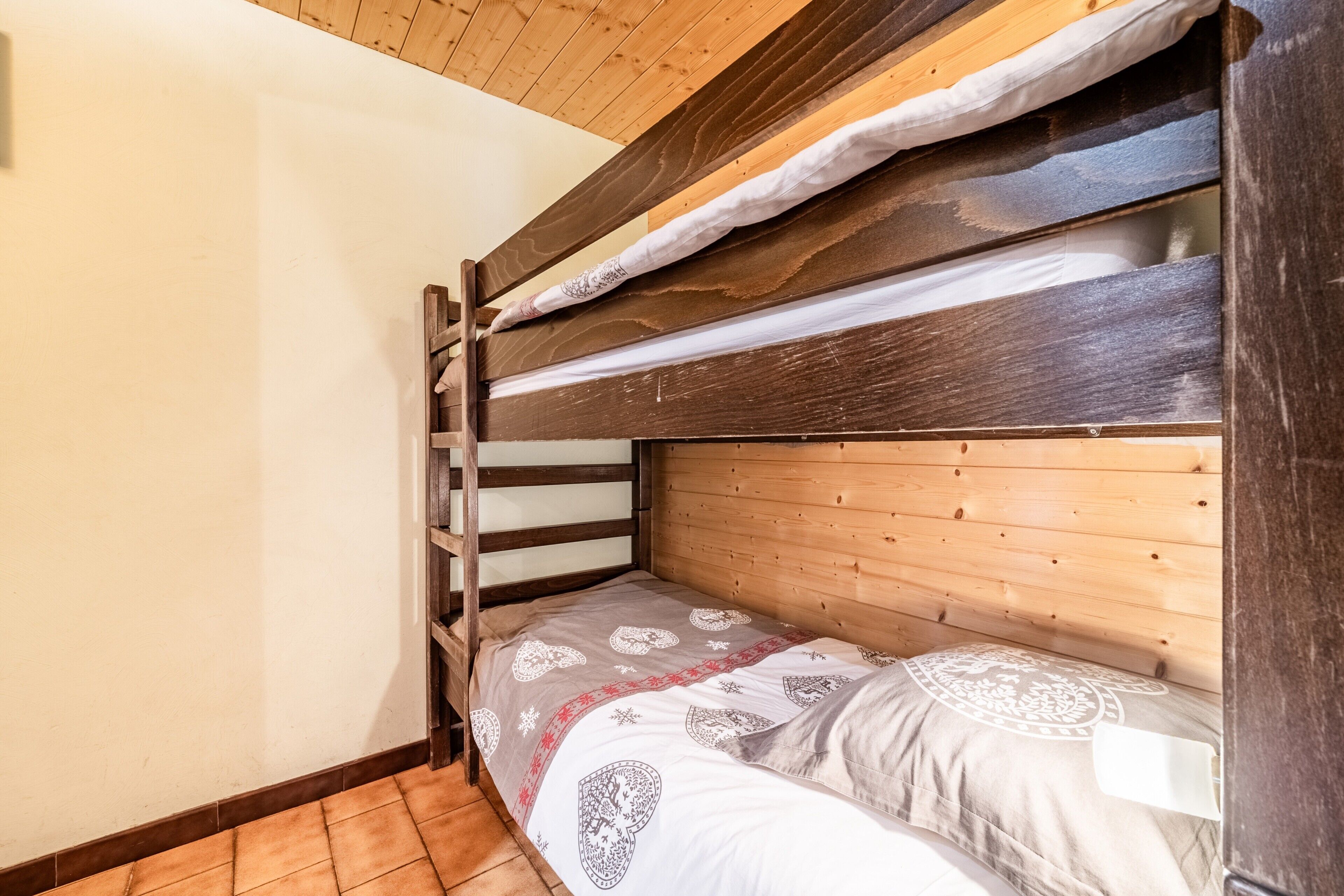 A bunk bed with a wooden headboard and a patterned bedspread.