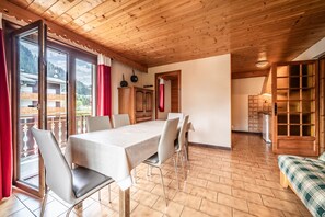 A dining area with a table and chairs, wooden ceiling, and a view of a mountain. - Apartment 'La Flèche De Vermeil - 6 Pers' with Mountain View, Balcony and Wi-Fi (Châtel)