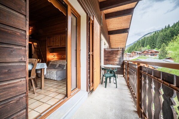 Une cabane en bois dotée d’un balcon, d’une table à manger et d’un canapé.