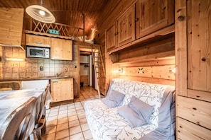 L’intérieur d’une cabane en bois comprend un coin cuisine, un canapé et un espace repas.