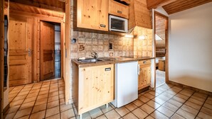 Una cocina de madera con salpicadero de azulejos, horno empotrado y un lavamanos.