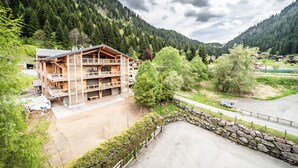 Eine mehrstöckige Holzlodge mit Balkonen, eingebettet in eine gebirgige Landschaft.