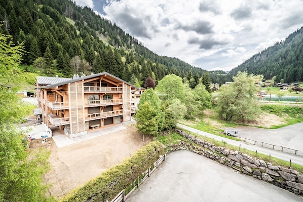 Un chalet en bois à plusieurs étages, doté de balcons et entouré d’un paysage montagneux.
