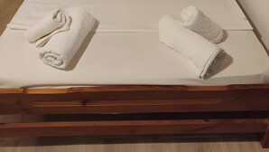A neatly made bed with pillows and towels, a wooden headboard, and a window with curtains. - Studio Apartment 'Corfu Oasis' with Mountain View, Wi-Fi and Air Conditioning (Corfu)