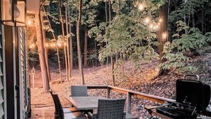 Eine Holzterrasse mit Gartenmöbeln, einem Grill und Lichterketten.