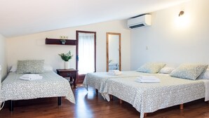 Une chambre avec deux lits, un petit bureau, un miroir et un appareil de climatisation.