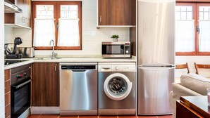 Une cuisine compacte équipée d’un lave-vaisselle, d’une machine à laver, d’un four à micro-ondes et d’un réfrigérateur.