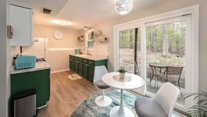 A modern kitchen with a dining area, large windows, and a view of the forest. - Pets~Trails~Beaches~10mins to TC~2 Person Suite (Williamsburg)