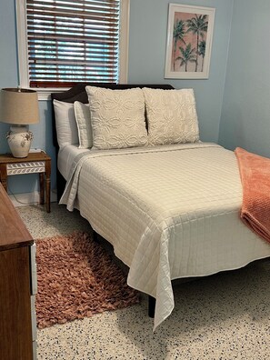 Cozy retreat with a neatly made bed, nightstand, and framed artwork.