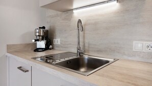 A modern kitchen with a stainless steel sink, a coffee maker, and a light under the countertop. - Apartment 'Haus Stolz Rebenblick' with Mountain View, Wi-Fi and Air Conditioning (Unterrain/Eppan a. d. Weinst)