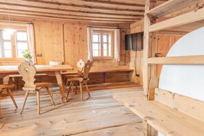 Un interno in legno con un tavolo da pranzo, sedie, una panca e un televisore.