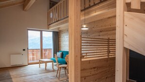 A room with wooden flooring, a sofa, a table, and a window with a view.