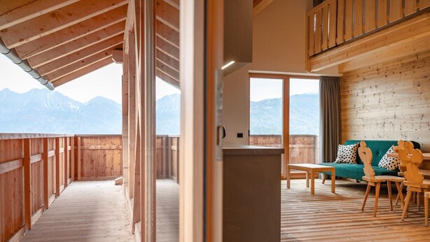 A wooden interior with a balcony, a sofa, and a table.