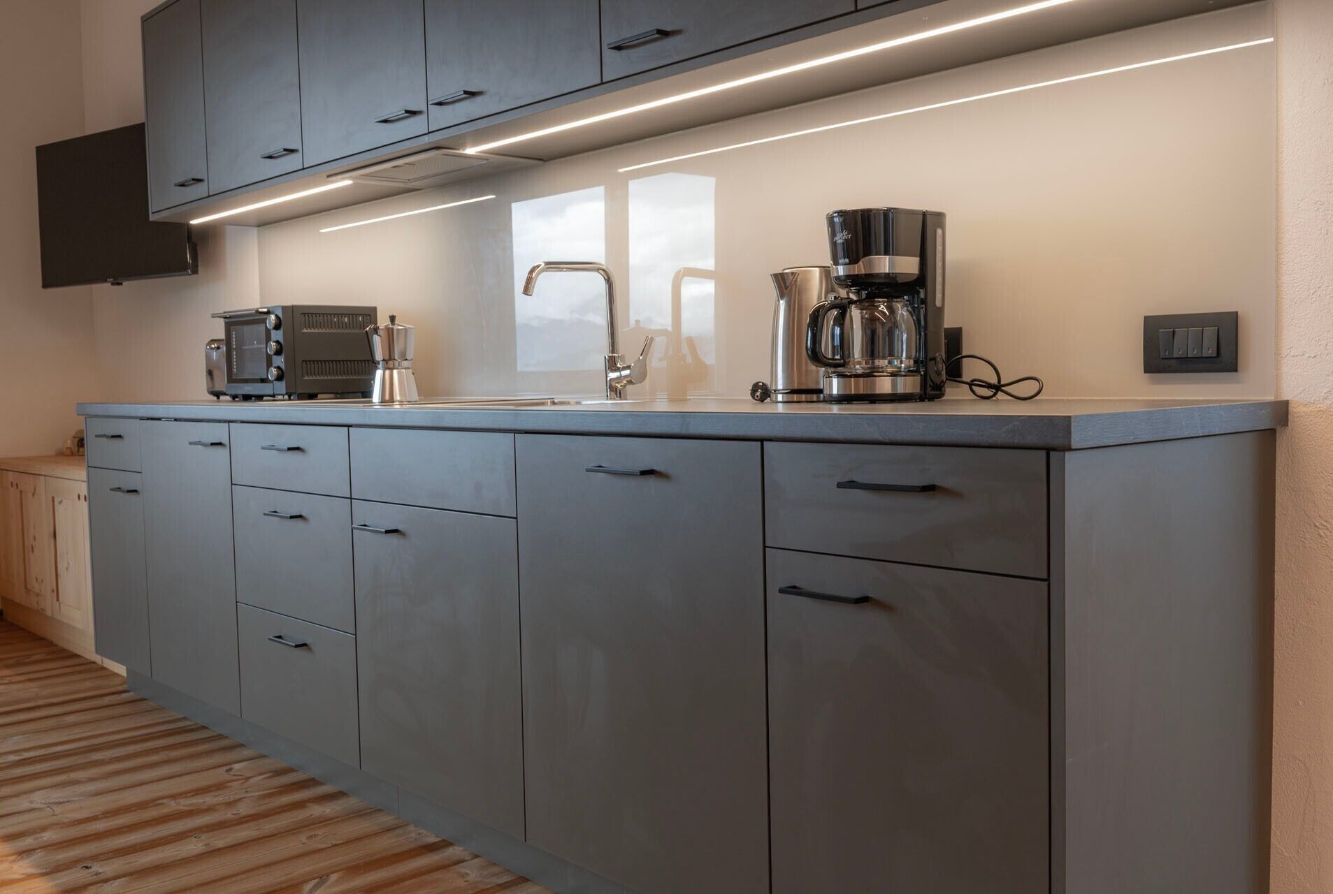 A kitchen with grey cabinets, a coffee maker, and a microwave.