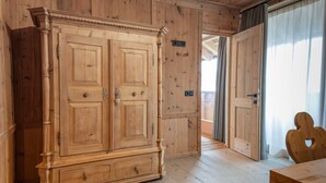 A wooden room with a large wardrobe, a door leading to a balcony, and a heart-shaped cutout on a wooden table. - Apartment 'Peunt' with Mountain View, Shared Terrace and Wi-Fi (Percha BZ)