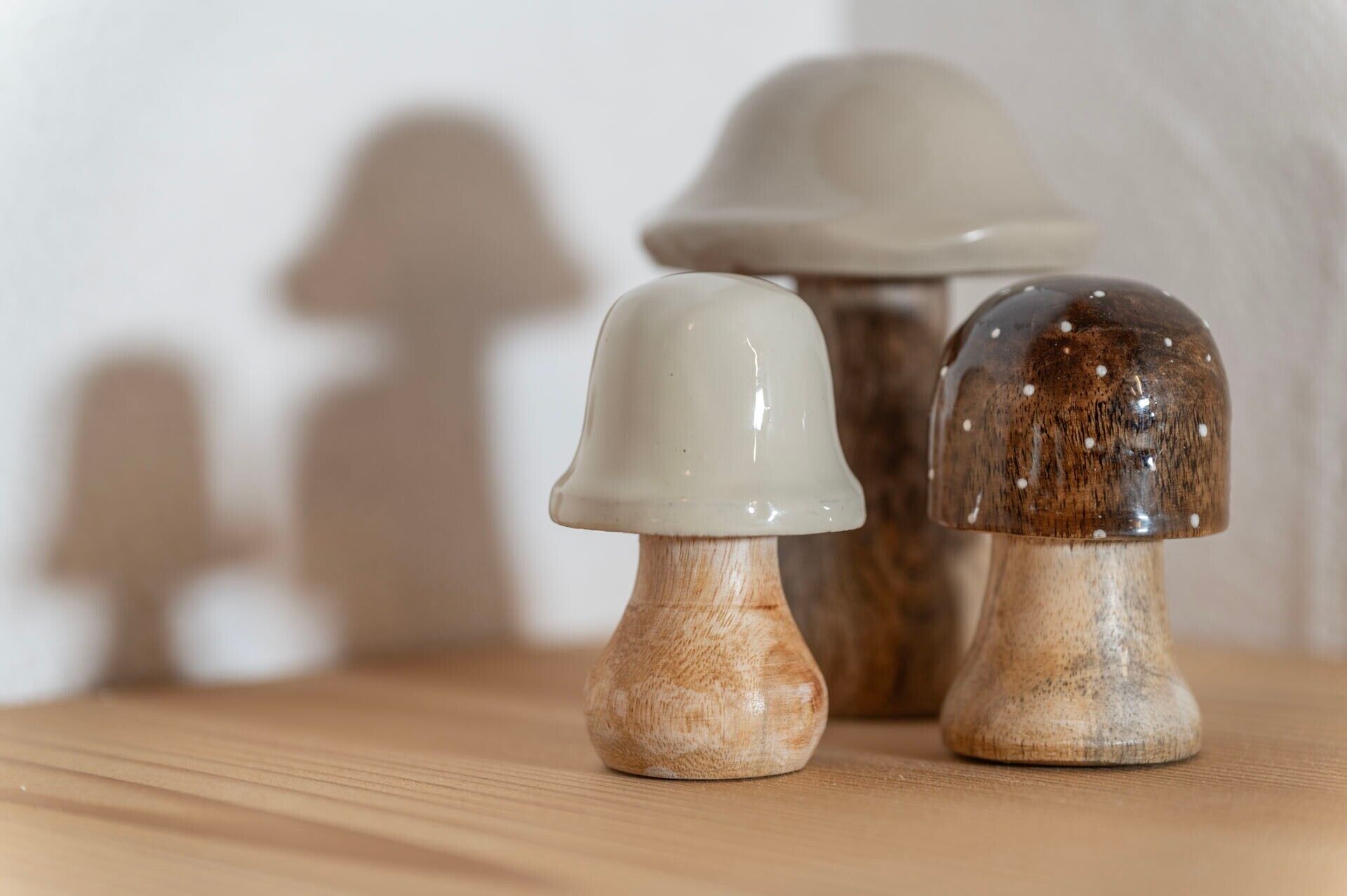 Trois salières et poivrières en forme de champignon, posées sur une surface en bois.