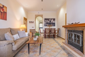 A living room with a sofa, coffee table, fireplace, and dining area.