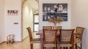 A dining area with a table, chairs, and a wall-mounted painting. - Holiday Home 'León' with Private Terrace, Wi-Fi and Air Conditioning (Almodóvar del Río)