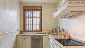 A kitchen with a dishwasher, a window, and a countertop with a stove. - Holiday Home 'León' with Private Terrace, Wi-Fi and Air Conditioning (Almodóvar del Río)