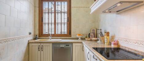 A kitchen with a dishwasher, a window, and a countertop with a stove.