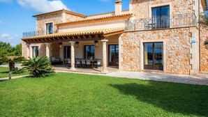 A two-story stone house with a covered patio, large windows, and a stone facade. - Country House 'Fortuna' with Mountain View, Private Pool and Wi-Fi (Manacor)