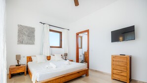 A bedroom with a wooden bed, a nightstand, a dresser, a flat-screen TV, a window with curtains, and a wall-mounted artwork. - Country House 'Fortuna' with Mountain View, Private Pool and Wi-Fi (Manacor)