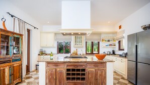 A modern kitchen with a central island, wooden cabinets, a stainless steel refrigerator, and a checkered floor. - Country House 'Fortuna' with Mountain View, Private Pool and Wi-Fi (Manacor)