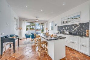 A modern kitchen with a large island, white cabinets, and a view of palm trees. - Villa 'Hakuna Matata' with Sea View, Wi-Fi and Air Conditioning (Marbella)