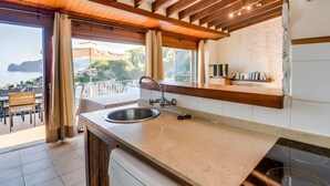 A kitchen with a large window, a sink, and a wooden ceiling. - Holiday Home 'Cala Deia' with Sea View, Wi-Fi and Air Conditioning (Illes Balears)