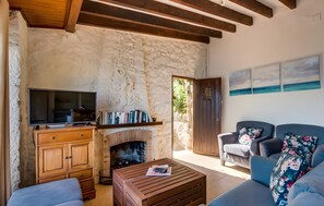 Une pièce aux murs de pierre, dotée d’une cheminée, d’un téléviseur, d’un canapé et d’une table basse.