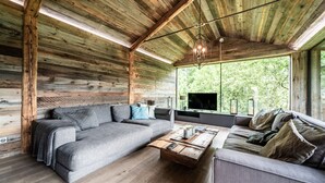 A log cabin interior with a gray sofa, a wooden coffee table, and a television.